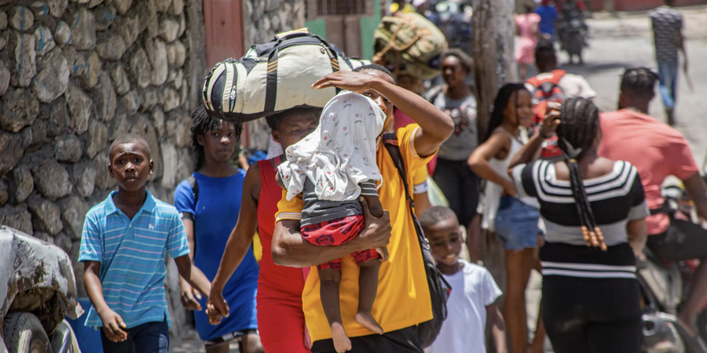 Displaced by escalating violence, families in Haiti carry their belongings as they flee their homes in search of safety.