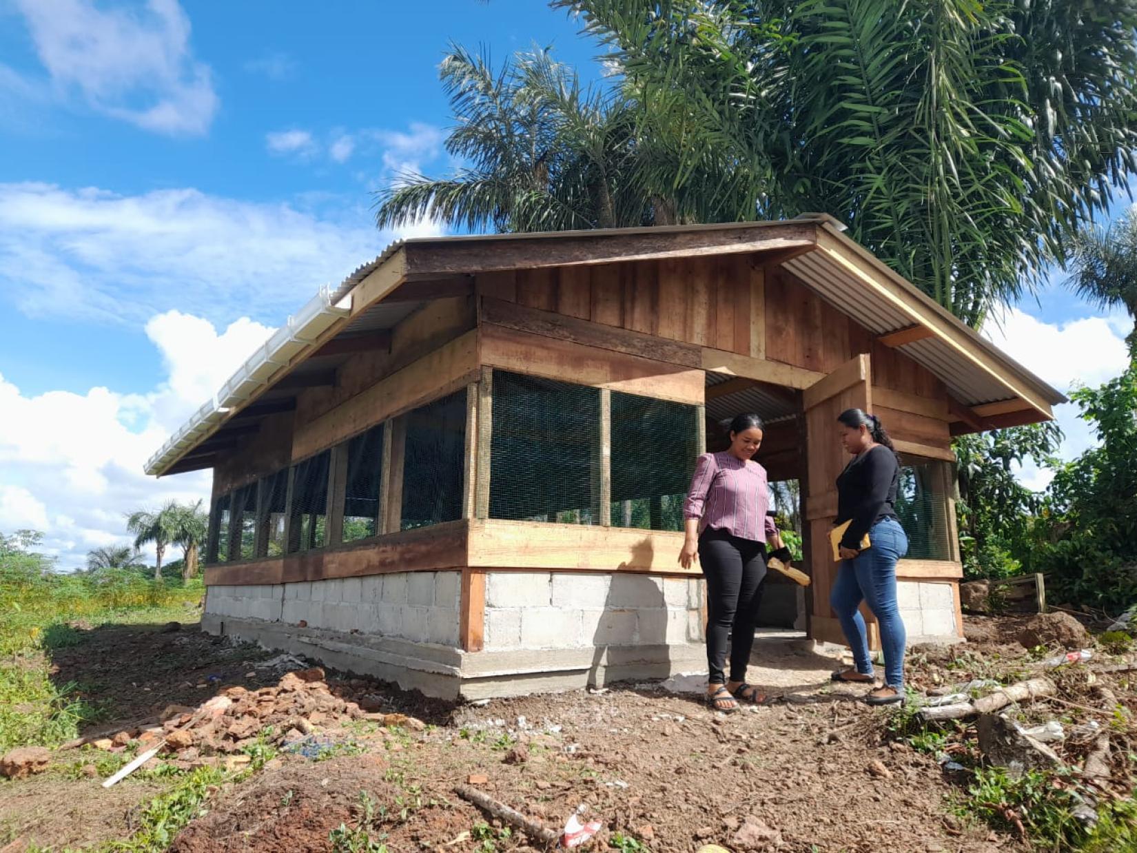 Two women standing at the door of a screened hut on a clear day