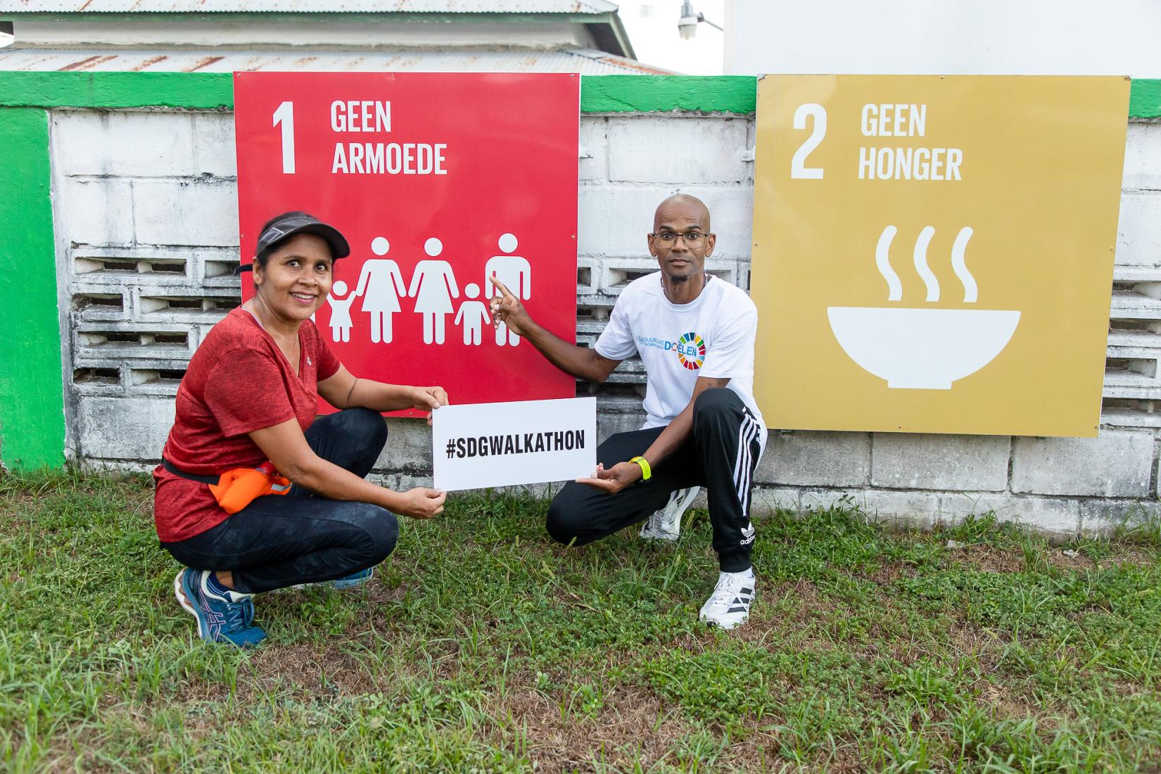 SDG Walkathon participants showcase the event's hashtag while posing infront of an SDG display along the route.