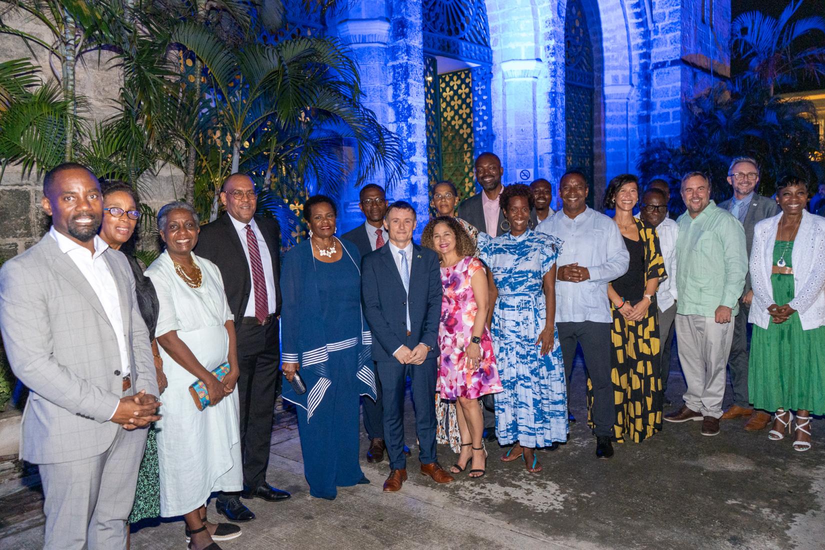 UN Resident Coordinator , Didier Trebucq (centre) is flanked by President of Barbados, Her Excellency Dame Sandra Mason  (left)  and PAHO/WHO Representative for Barbados and the Eastern Caribbean, Dr. Amalia Del Riego (right) , along with Minister of Foreign Affairs the Honorable Kerrie Symmonds (4th from left)  and other Government and UN officials , shortly after flicking the switch to illuminate the Parliament building.