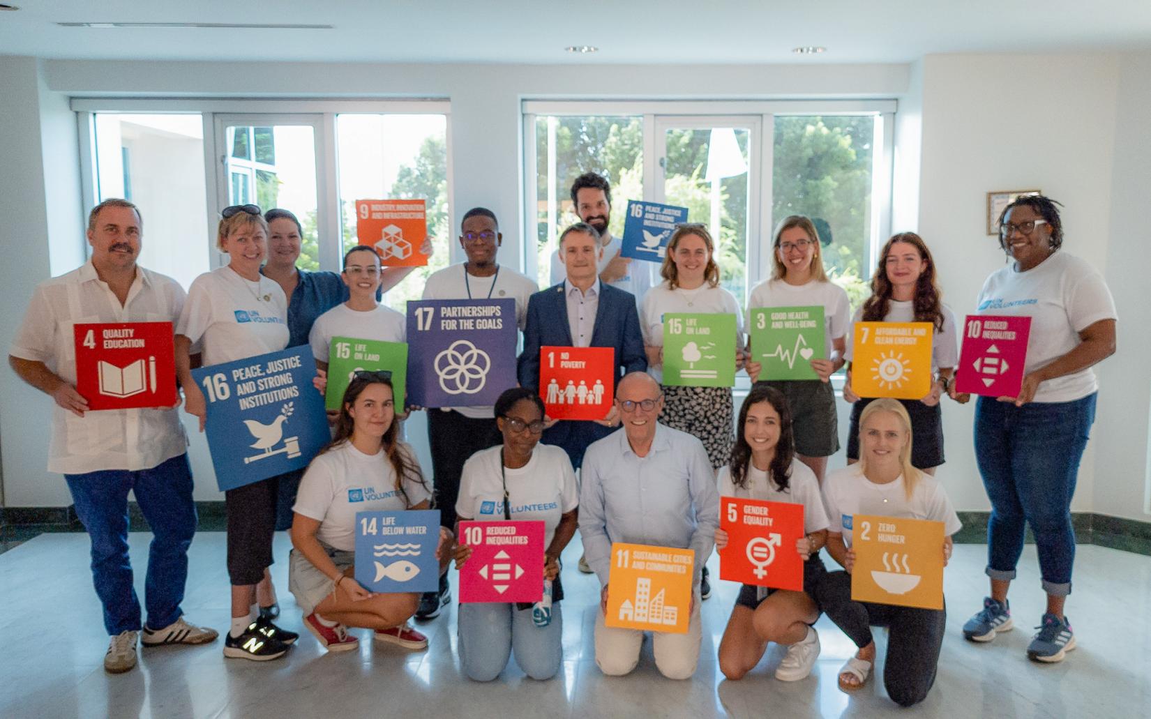 A group photo of the UNVs holding SDG Cards with members of the UN Subregional Team. 