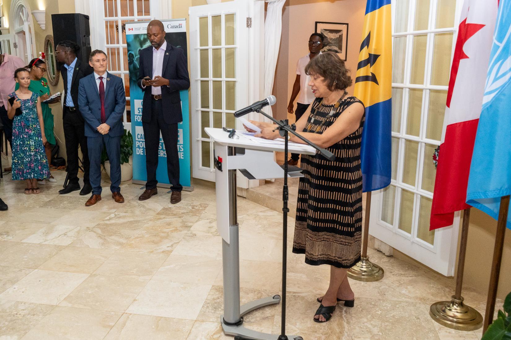 Canadian High Commissioner Lilian Chatterjee delivers an address from a podium