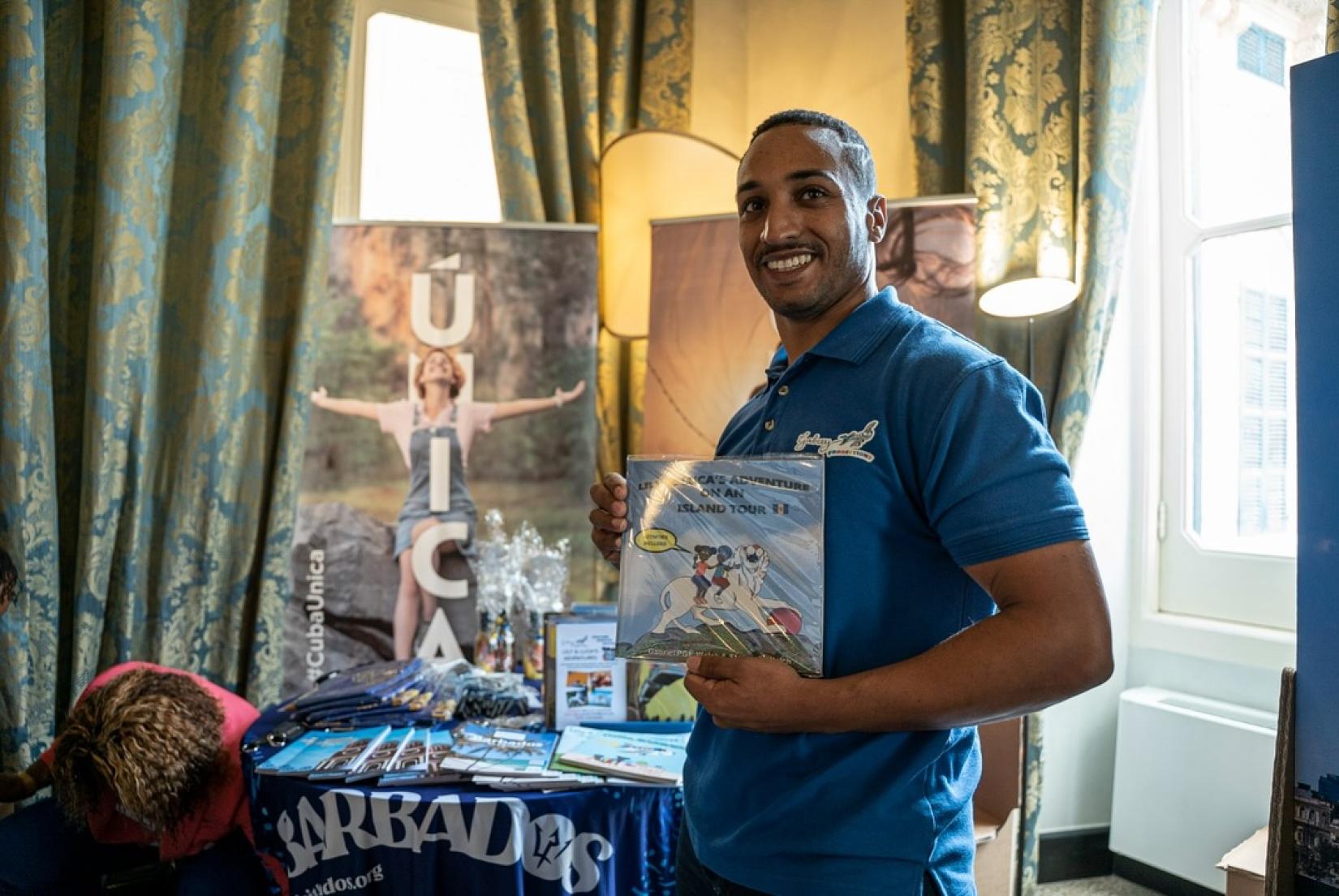 Barbadian tourism guide and designer Gabriel Welch with a book he co-authored from a series of children's books promoting the heritage of Barabados and the Caribbean.