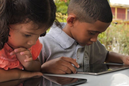 Two Venezuelan children use tablets at school in Trinidad and Tobago.