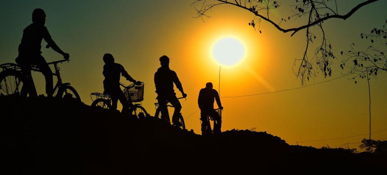 silhouettes of 4 people riding bikes and looking towards the sun