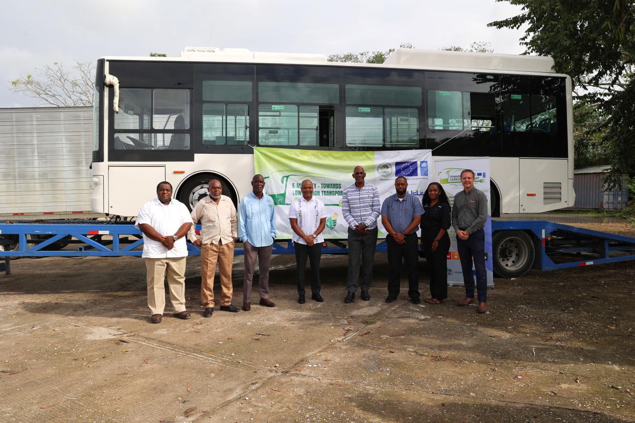Eight stakeholders stand in front of a new electric bus in Belize