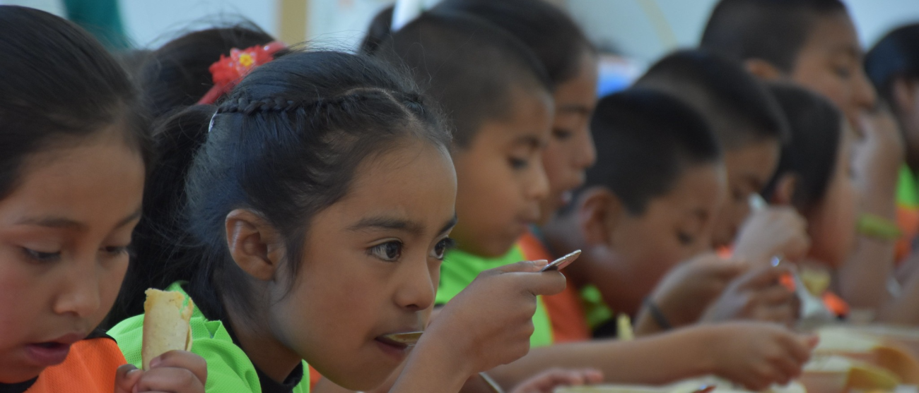 Children seated at a table, eating.