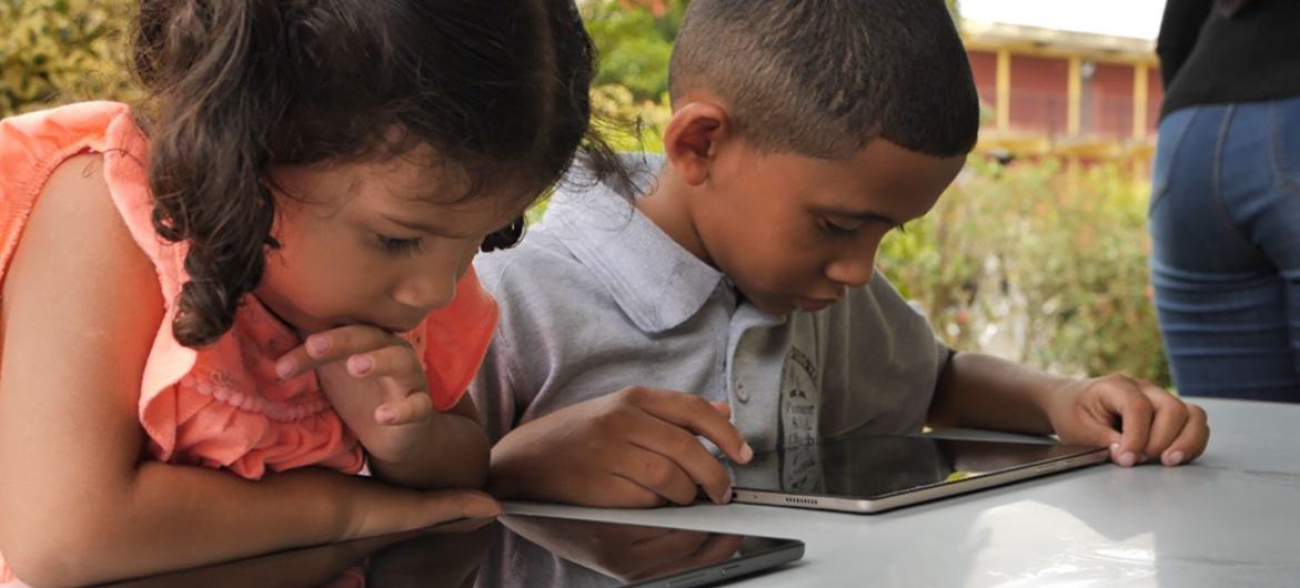 Two Venezuelan children use tablets at school in Trinidad and Tobago.