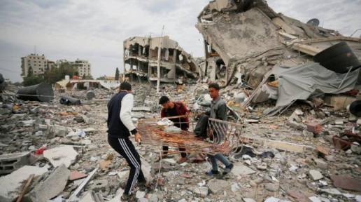 three men attempt to recover items from rubble among collapsed buildings in Gaza