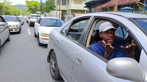 A man gestures in frustration from inside of his vehicle in response to traffic congestion