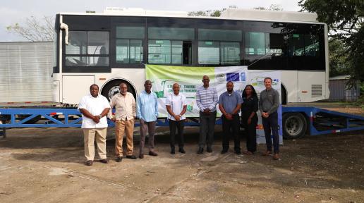 Eight stakeholders stand in front of a new electric bus in Belize