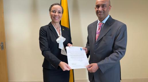 Kishan Khoday presents his credentials to the Minister in front of a UN flag and a Jamaica flag.