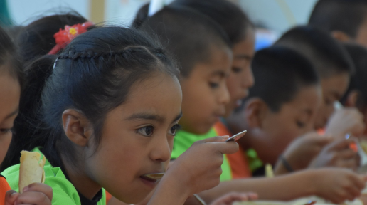 Children seated at a table, eating.