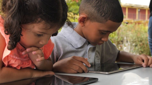 Two Venezuelan children use tablets at school in Trinidad and Tobago.